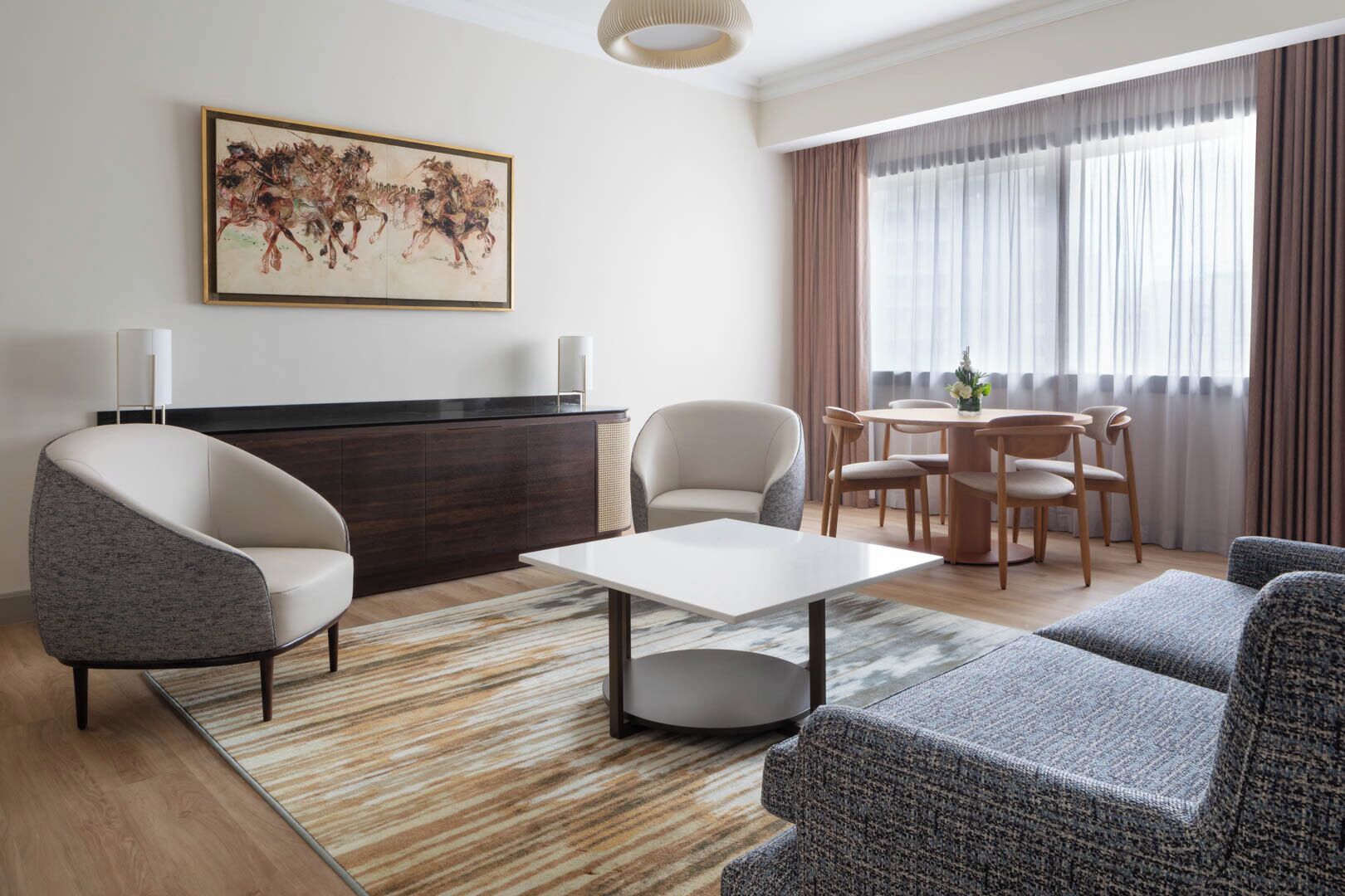 Un salon moderne avec un canapé, un fauteuil, une table à manger et un tableau accroché au mur.