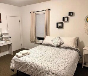Cozy retreat with a neatly made bed, bedside table, and wall-mounted picture frame.