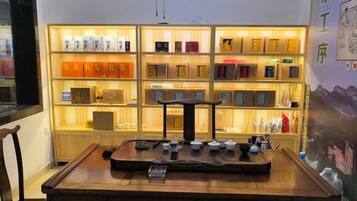 A wooden table with a tea set in front of a shelf with various items.