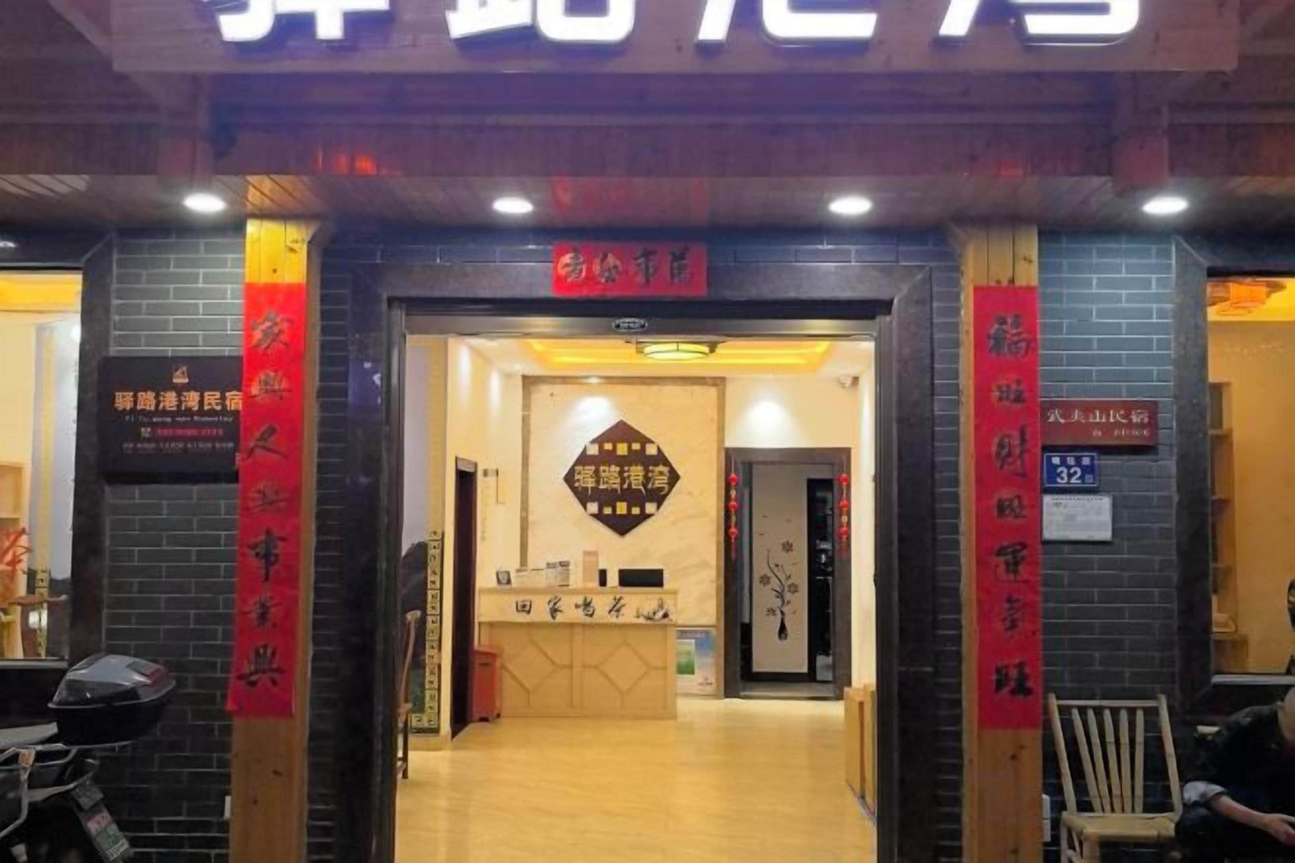 A hotel entrance with a reception desk, a signboard, and a red banner.
