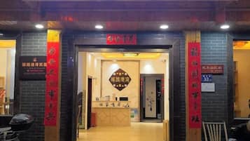 A hotel entrance with a reception desk, a signboard, and a red banner.