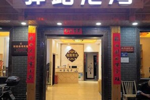 A hotel entrance with a reception desk, a signboard, and a red banner. - Yilu Gangwan Inn (Wuyishan)