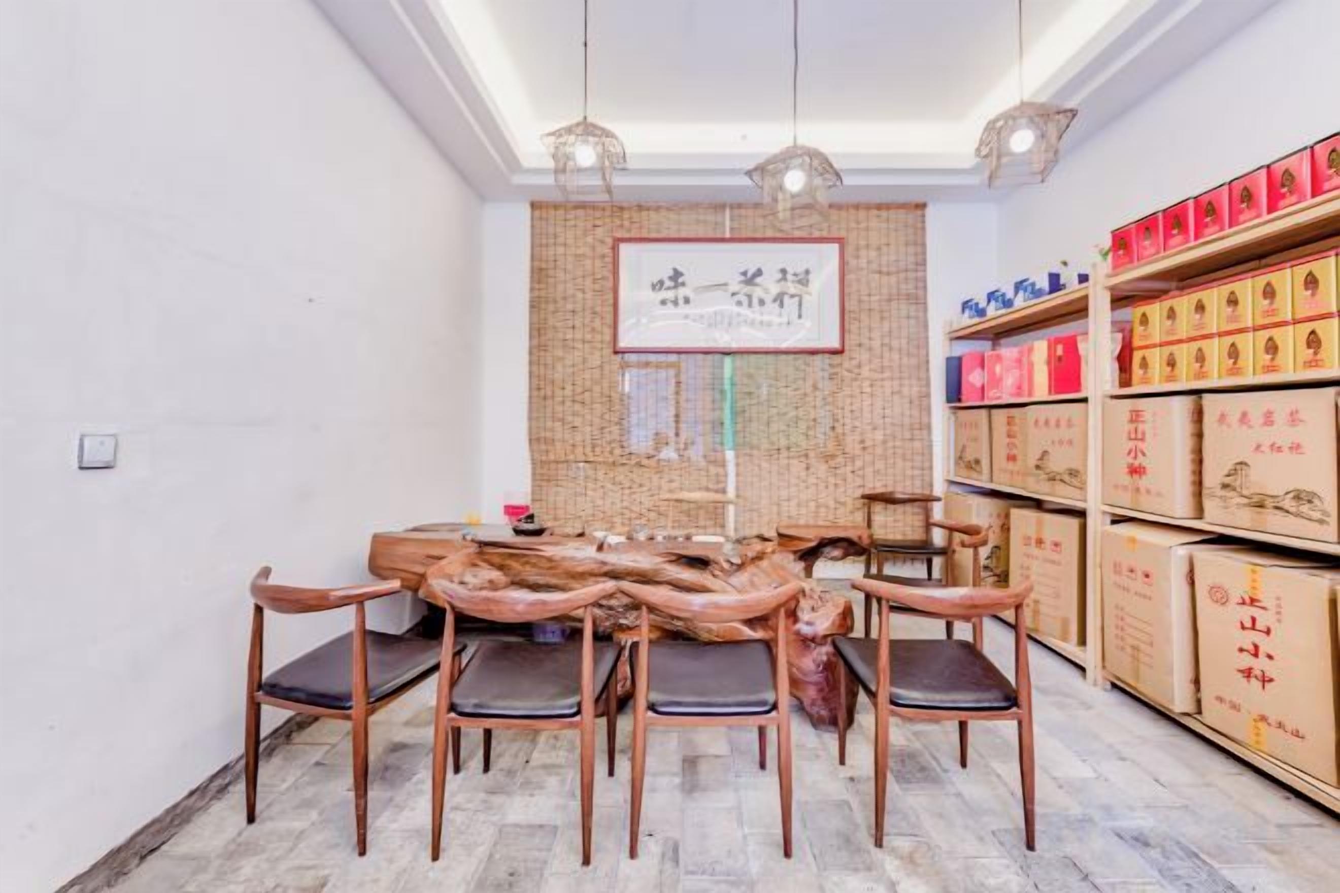 Un comedor con mesa y sillas de madera, una pared con un cuadro enmarcado, y estanterías con cajas.