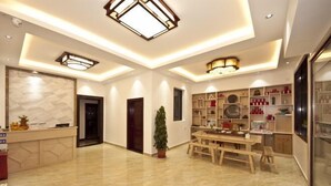 A spacious room with a marble floor, a wooden dining table, and a reception desk. - Yilu Gangwan Inn (Wuyishan)
