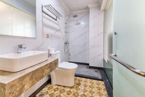 A bathroom with a marble sink, toilet, and shower. - Yilu Gangwan Inn (Wuyishan)
