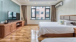 A hotel room with a large window, a flat-screen TV, wooden flooring, and a bed with white bedding. - Yilu Gangwan Inn (Wuyishan)