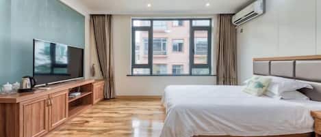 A hotel room with two beds, a TV, a wooden cabinet, and a large window.