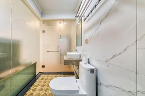 A compact bathroom with a toilet, sink, and glass shower enclosure. - Yilu Gangwan Inn (Wuyishan)