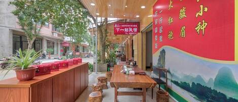 Un restaurante con techo de madera, pared roja con caracteres chinos y una mesa con taburetes.