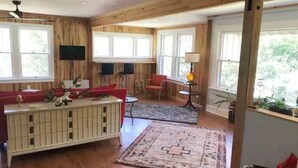 A wooden-paneled room with a white console table, red chairs, and a patterned rug. - Awesome House in Downtown Sylva! (Sylva)