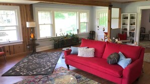 A cozy living room with a red sofa, patterned rugs, and a glass coffee table. - Awesome House in Downtown Sylva! (Sylva)