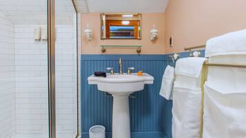 A bathroom with a white sink, blue wall paneling, a mirror, and a towel rack with white towels.