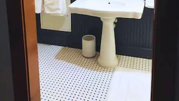 Een badkamer met een witte wastafel, een ronde spiegel en twee wandlampen.