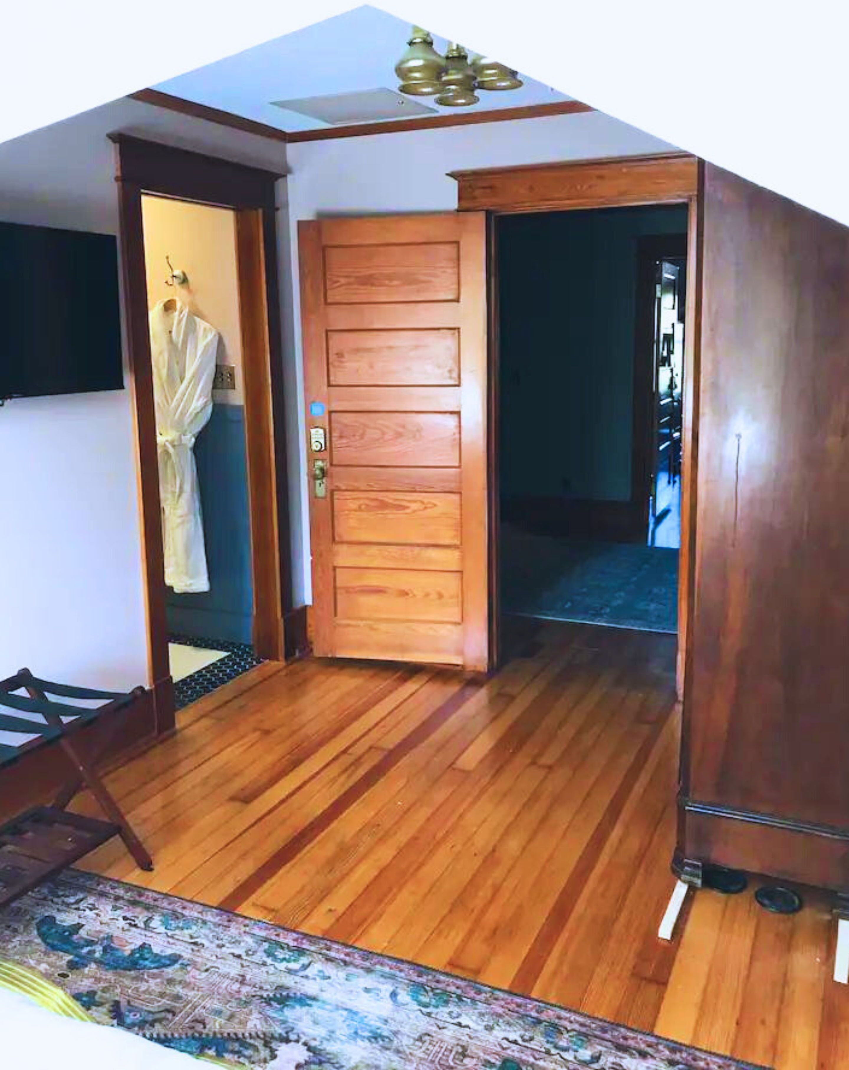 Una habitación con puerta de madera, una cama pequeña y suelo de madera.