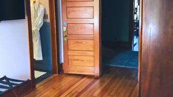 Una habitación con puerta de madera, una cama pequeña y suelo de madera.