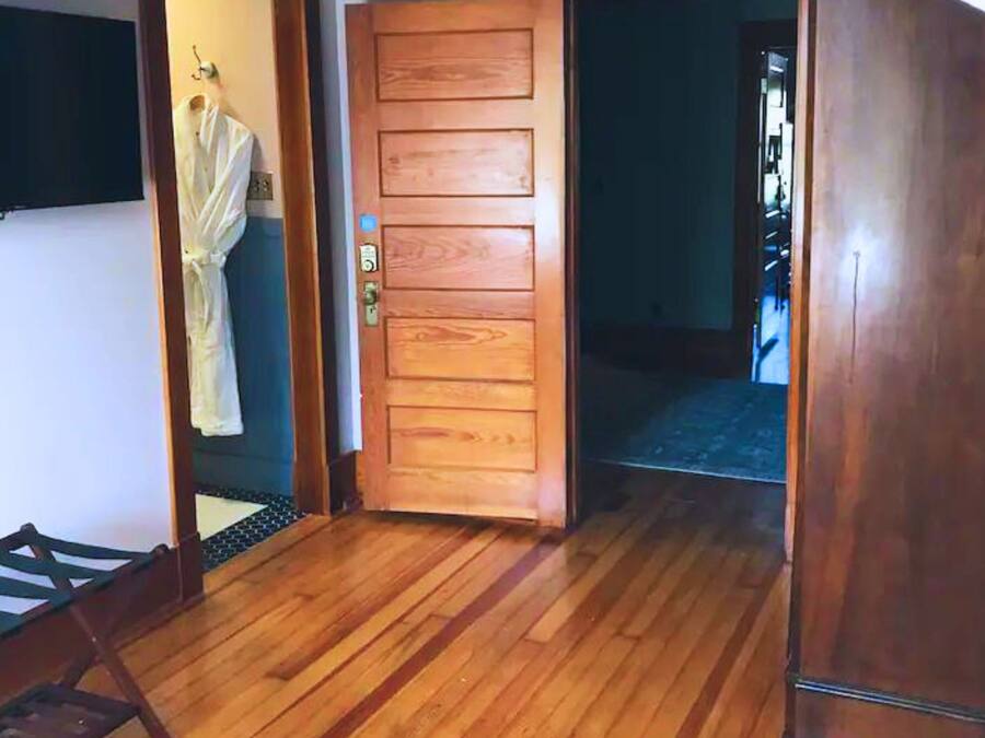 Una habitación con puerta de madera, una cama pequeña y suelo de madera.