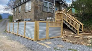 A stone house with a wooden staircase leading to a deck. - Not available (Sylva)