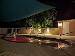 A swimming pool with a unicorn float, two chairs, and a covered area.