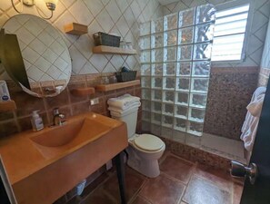 A bathroom with a sink, toilet, and a shower area with frosted glass panels.