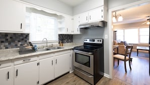 A modern kitchen with white cabinets, a stainless steel stove, and a granite countertop.