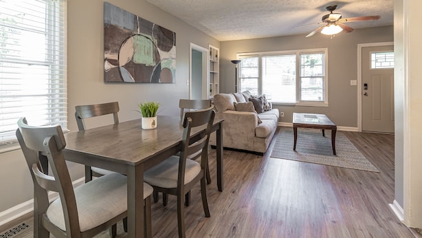 A spacious living area with a dining table, chairs, a sofa, and a ceiling fan.