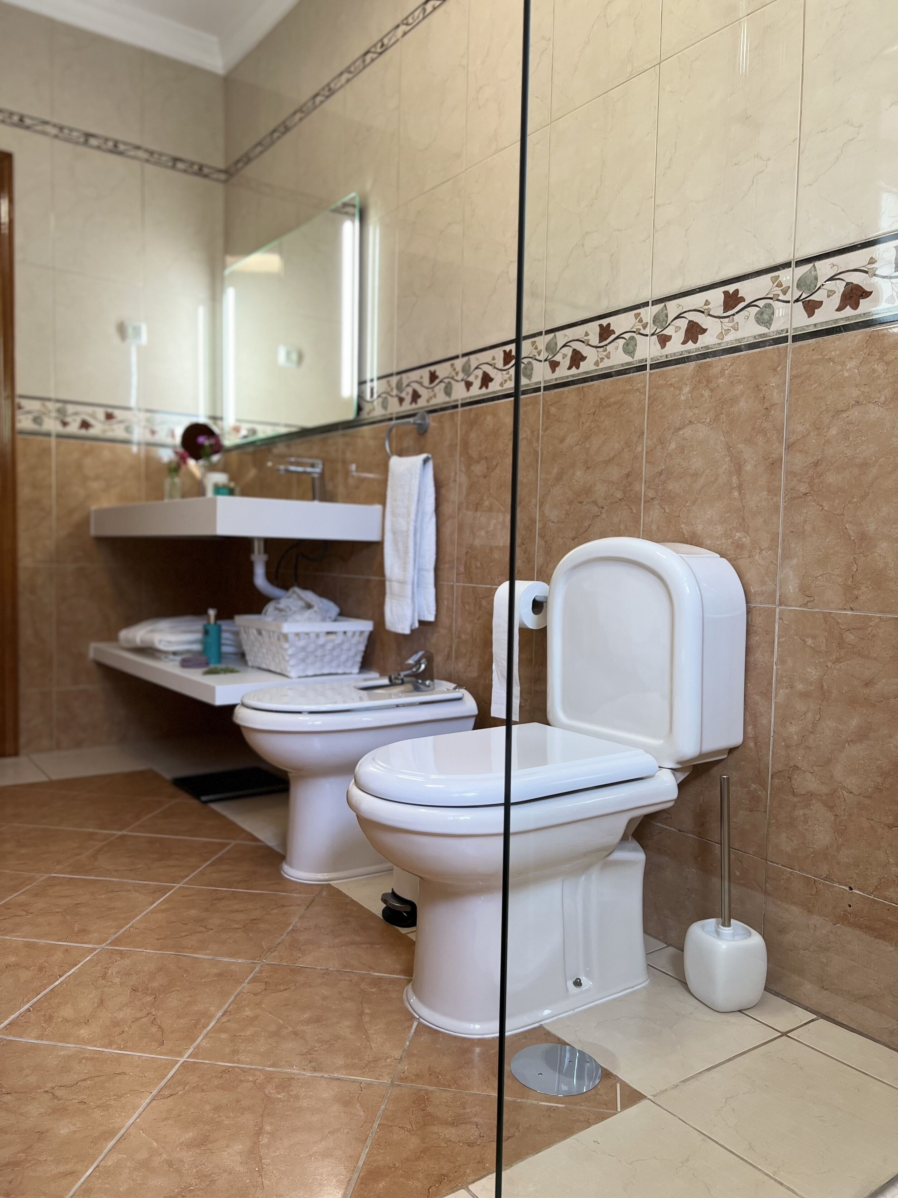 A modern bathroom with two toilets, a sink, and a mirror.