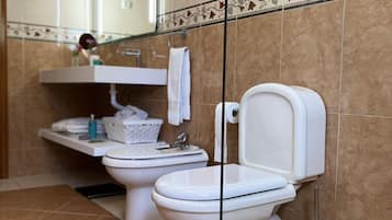 A modern bathroom with two toilets, a sink, and a mirror.