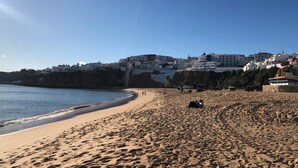 A beach with a clear sky, sandy shore, and buildings in the background. - Villa Tranberg (Silves)