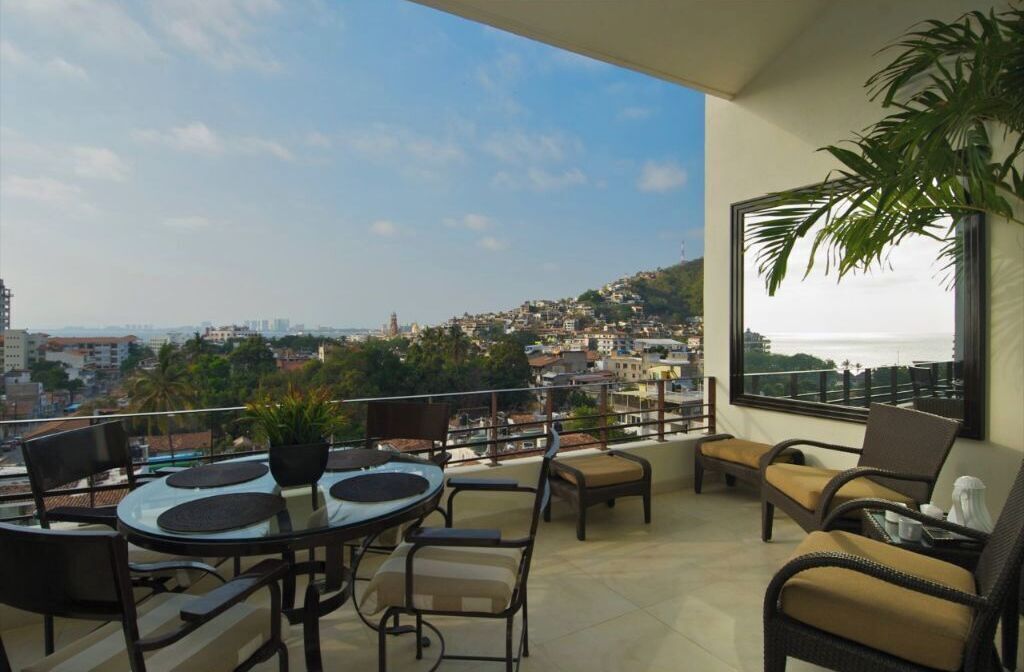 A balcony with a table and chairs, a potted plant, and a view of a cityscape.