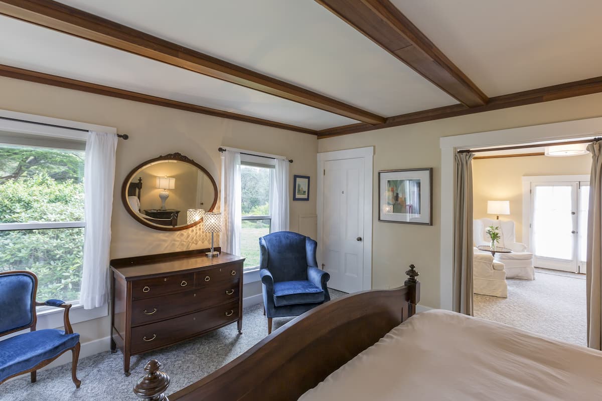 A bedroom with a bed, a dresser, a chair, and a large window with curtains.