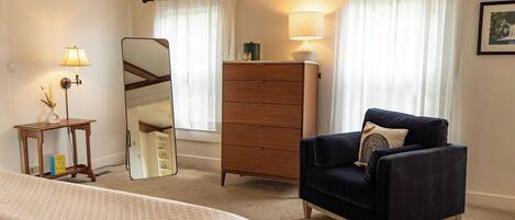 A hotel room with a bed, a dresser, a chair, a mirror, and two lamps.