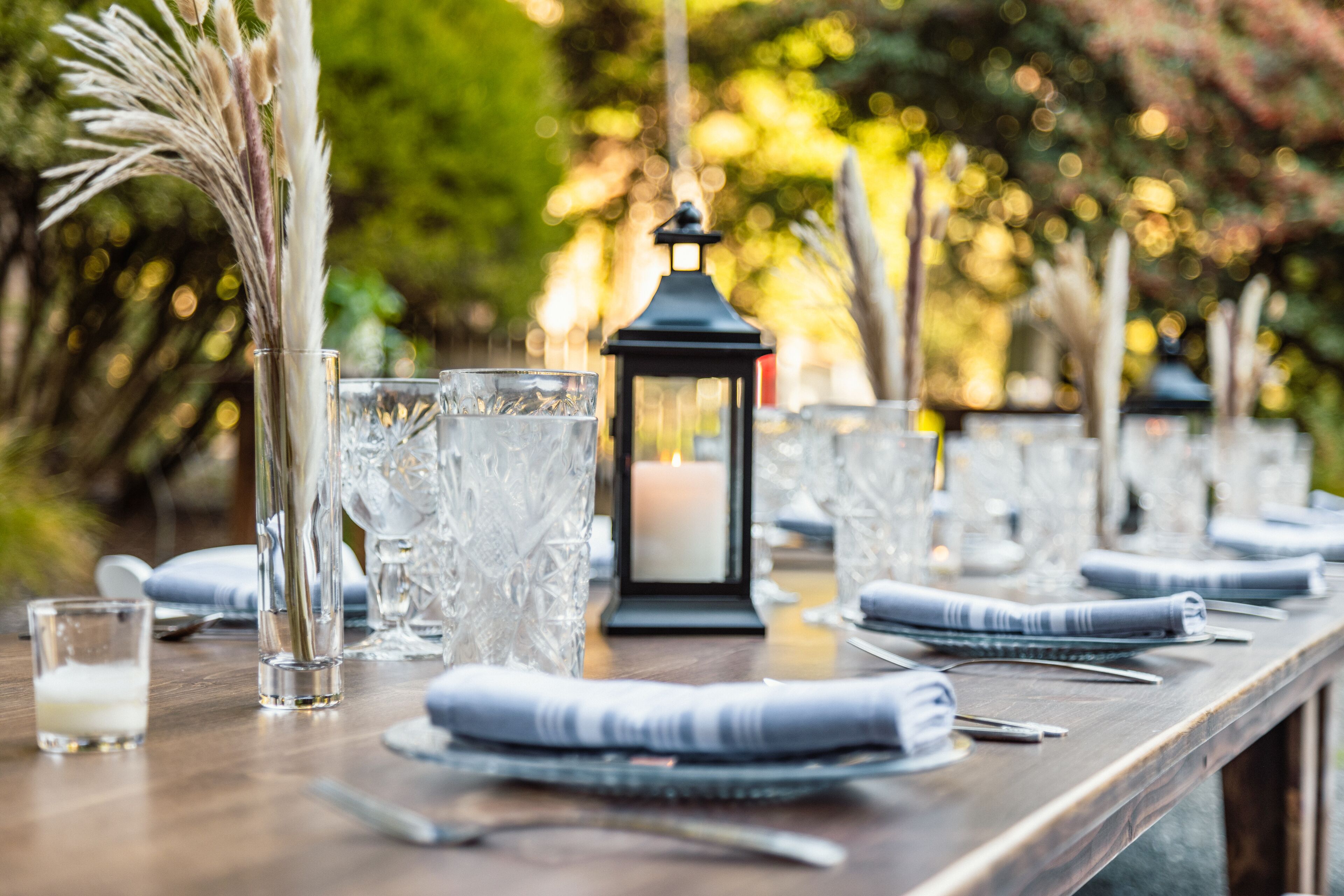Une table dressée avec de beaux verres, une bougie et une lanterne, ce qui évoque une ambiance de repas formel.