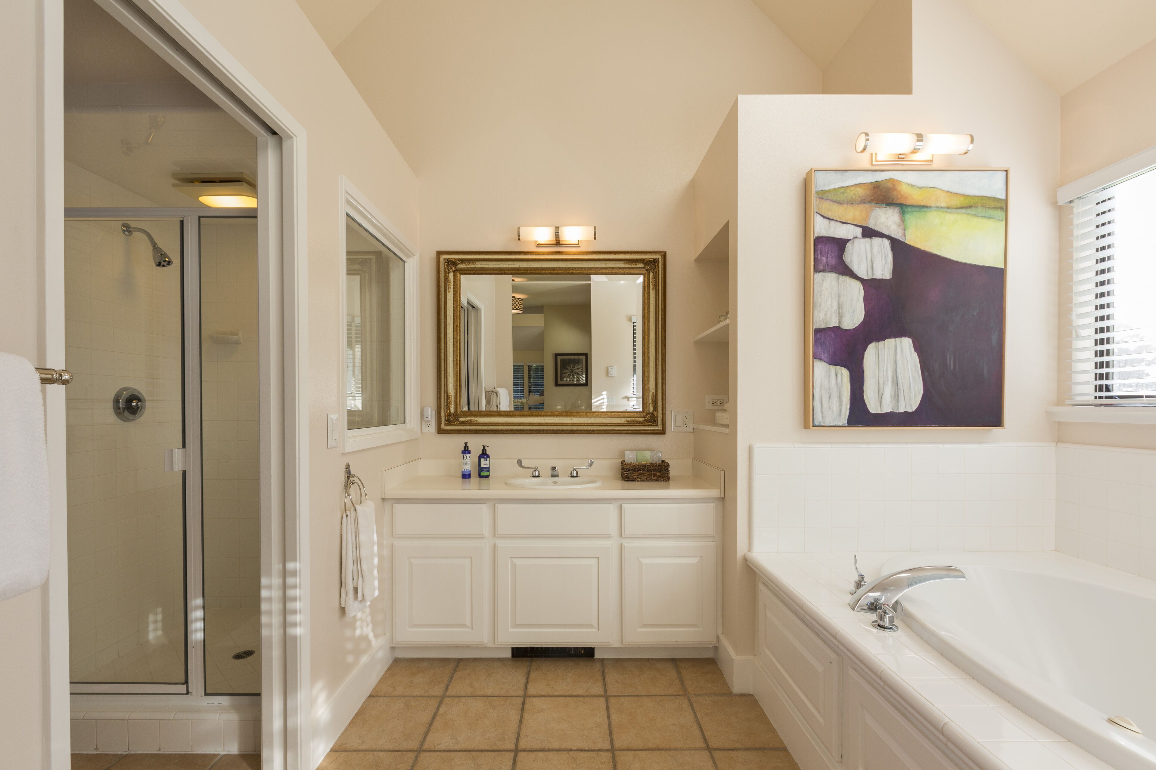 A bathroom with a walk-in shower, a large mirror, a bathtub, and a sink.