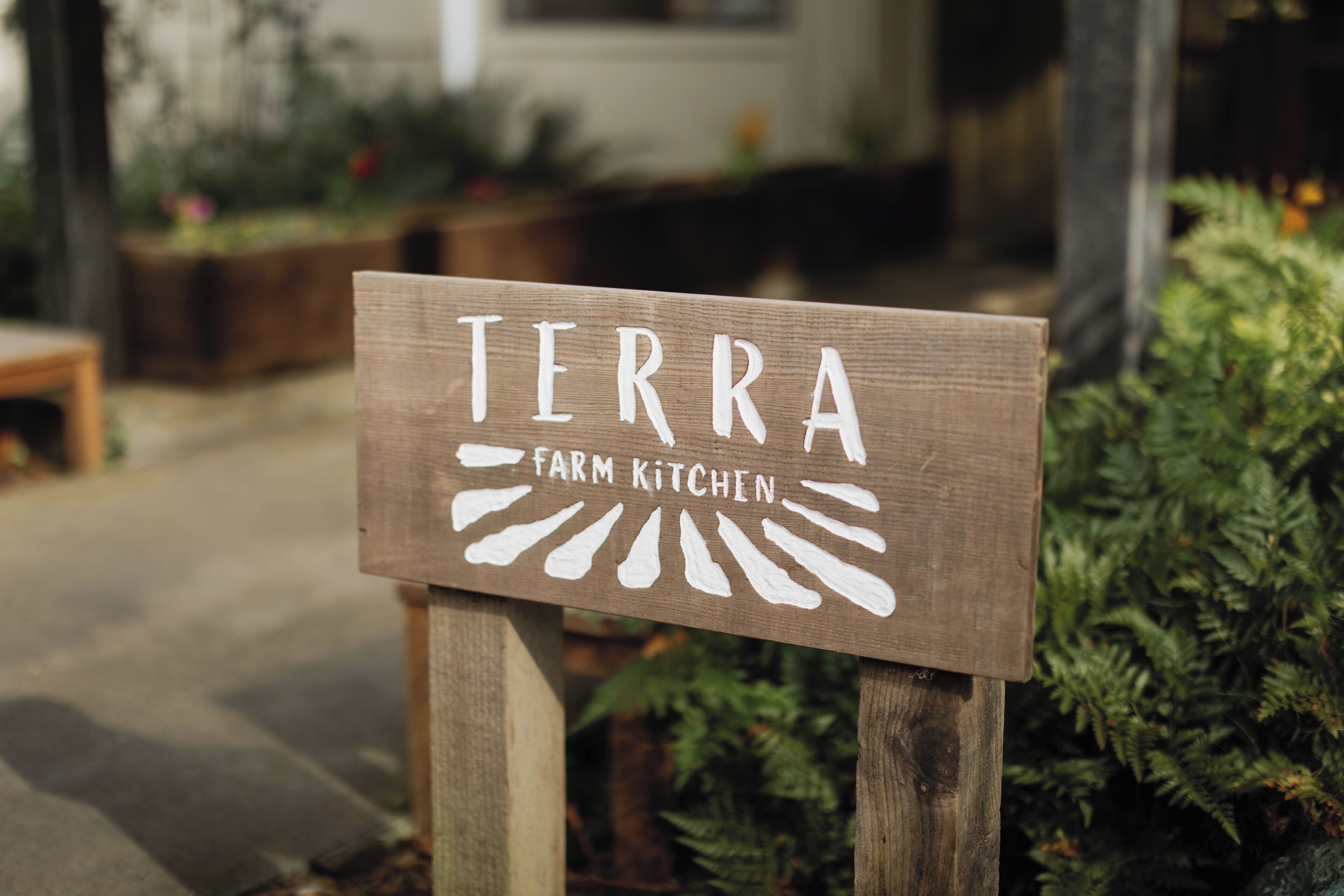 Un panneau en bois portant l’inscription « TERRA FARM KITCHEN », qui indique le nom du lieu.
