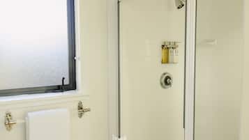 A bathroom with a glass shower door, a window, and a towel rack.