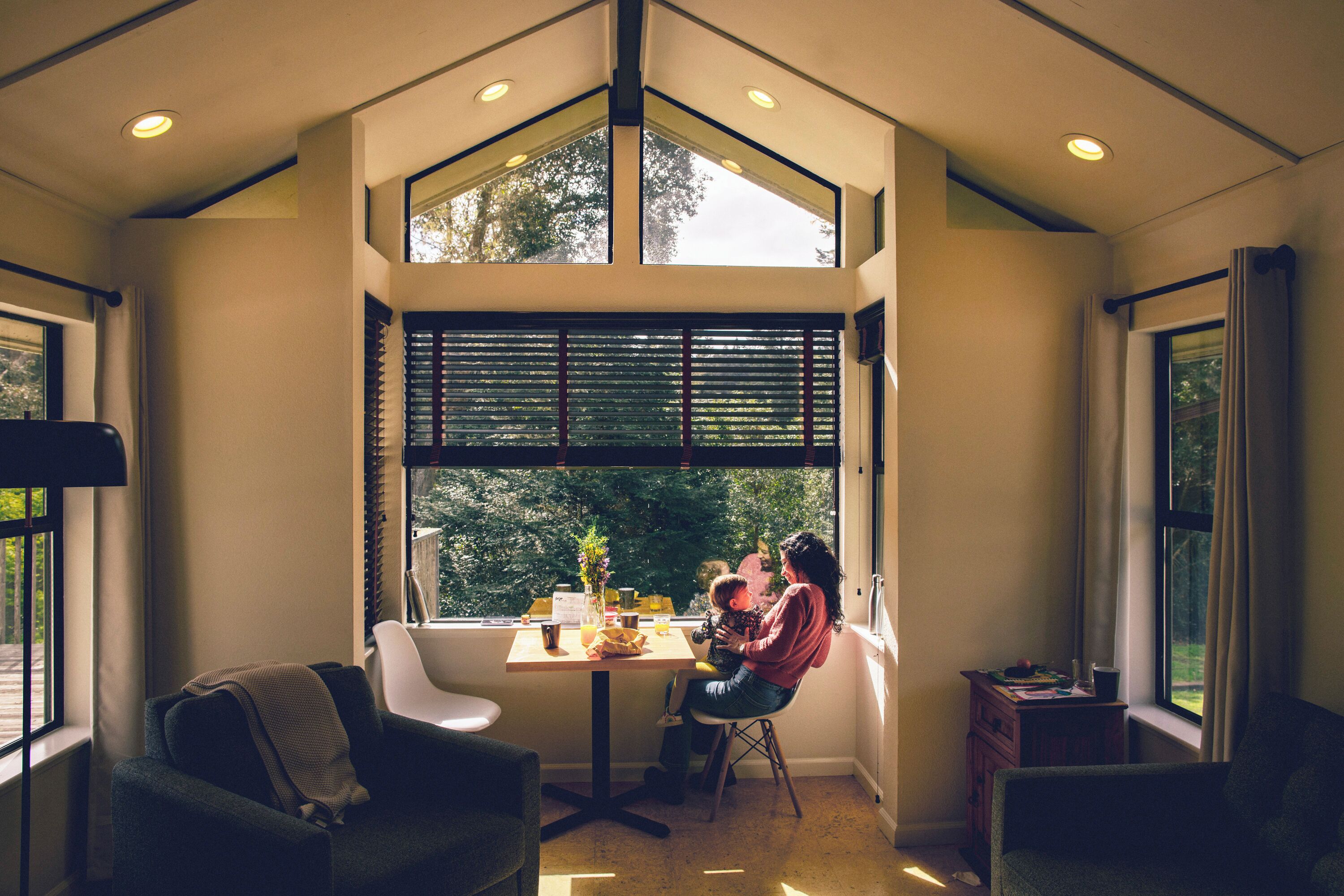 Una habitación de esquina con un ventanal grande, una mesa y una silla.