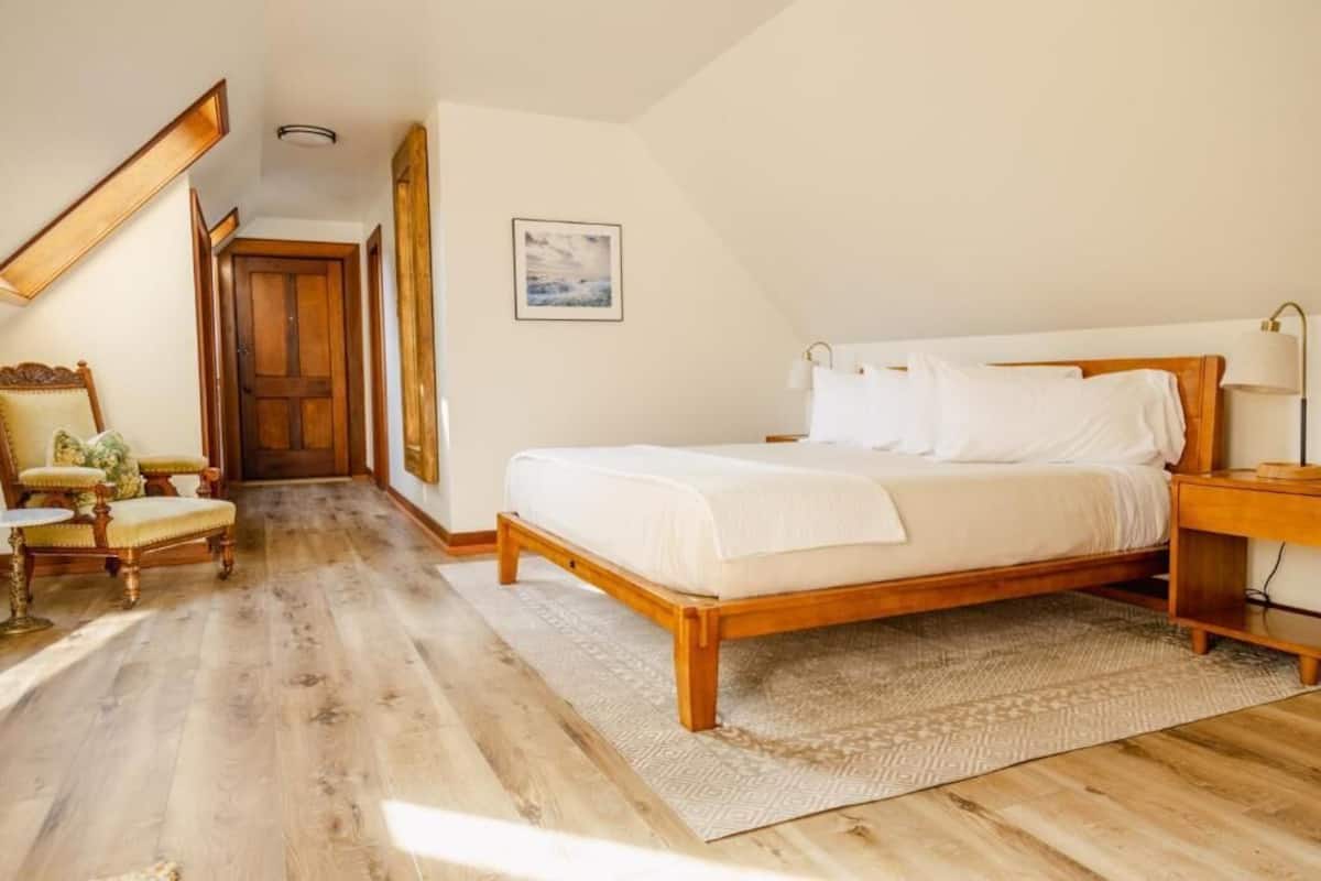A bedroom with a wooden bed, a nightstand, a chair, and a rug.