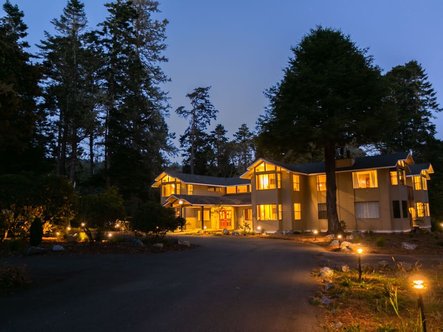A two-story house with a driveway and a well-lit entrance.