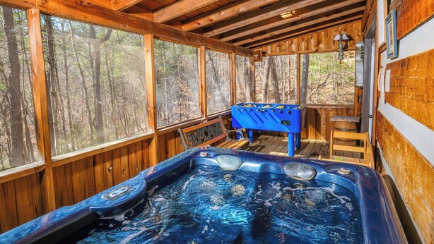 A wooden cabin with a hot tub, a foosball table, and a wooden deck. - Heaven in the Pines: Pure Bliss in the Smokies (Sevierville)
