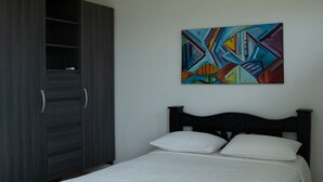 A bedroom with a bed, a wardrobe, and a colorful abstract painting on the wall. - Hogar Dorado Las Gaviotas (Puerto Colombia)