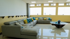 A modern living room with a sectional sofa, a round coffee table, and large windows. - Hogar Dorado Las Gaviotas (Puerto Colombia)
