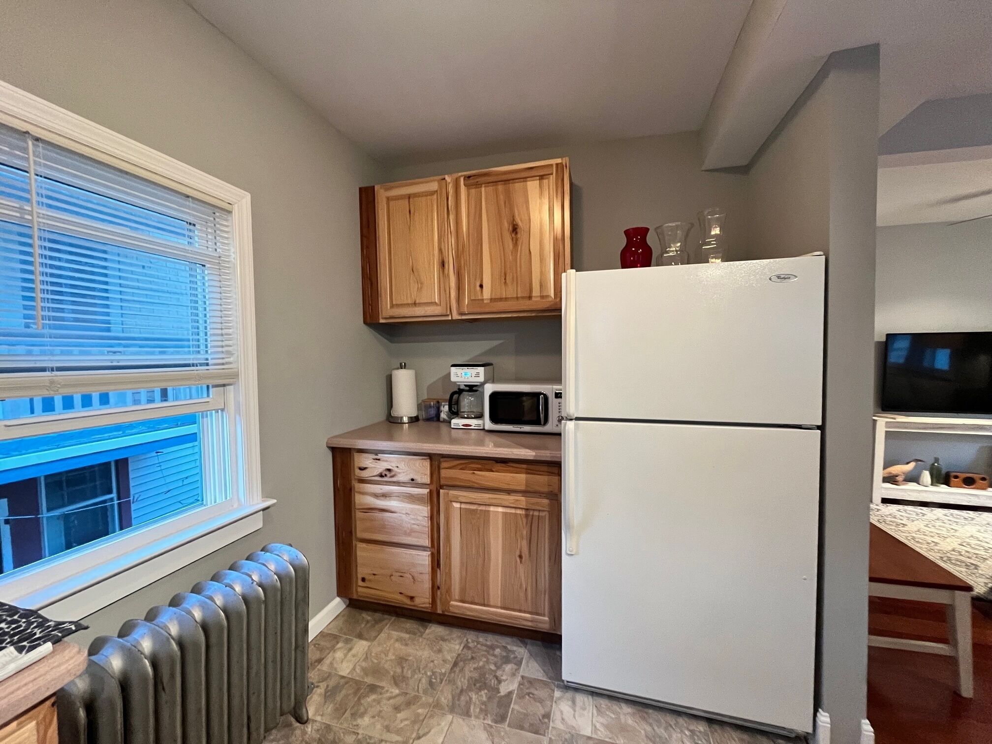 Une cuisine compacte avec des meubles de rangement en bois, un réfrigérateur blanc, un four à micro-ondes et une machine à café.