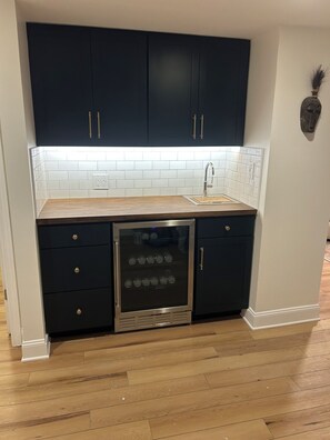 A kitchen with dark cabinets, a stainless steel refrigerator, and a white tiled backsplash.