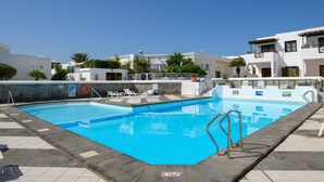 Une piscine à l’eau d’un bleu cristallin, entourée d’une terrasse carrelée et agrémentée d’un poste de surveillance pour les sauveteurs.