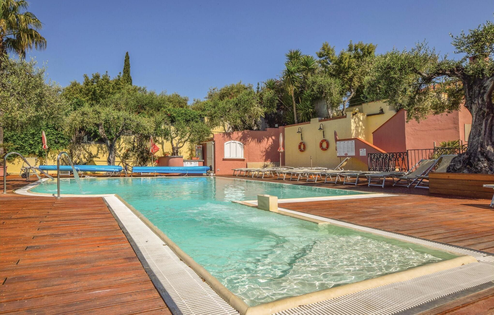 A swimming pool with lounge chairs and a wooden deck.