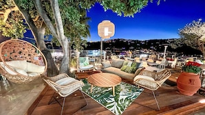 An outdoor seating area with wicker furniture, a round wooden table, and a decorative lantern. - Cozy apartment in Imperia with outdoor swimming pool (Imperia)