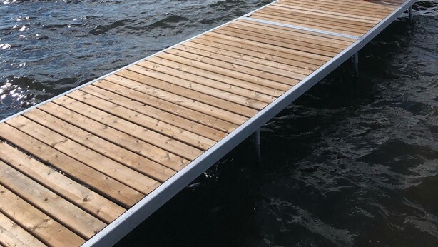 Une jetée en bois s’étendant dans un lac, avec des chaises rouges qui y sont disposées.