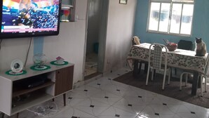 Una sala de estar con televisión, una mesa de comedor con sillas, un sofá y una ventana con vistas.