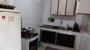Una cocina compacta con gabinetes blancos, una estufa y un lavamanos.