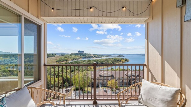 Ein Balkon mit Korbstühlen und Blick auf einen See sowie entfernte Gebäude.
